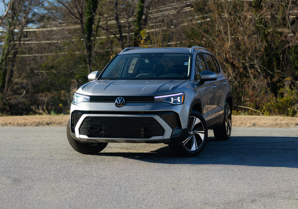 2026 Volkswagen Taos parked on a paved surface. It is facing the camera with its headlights on.