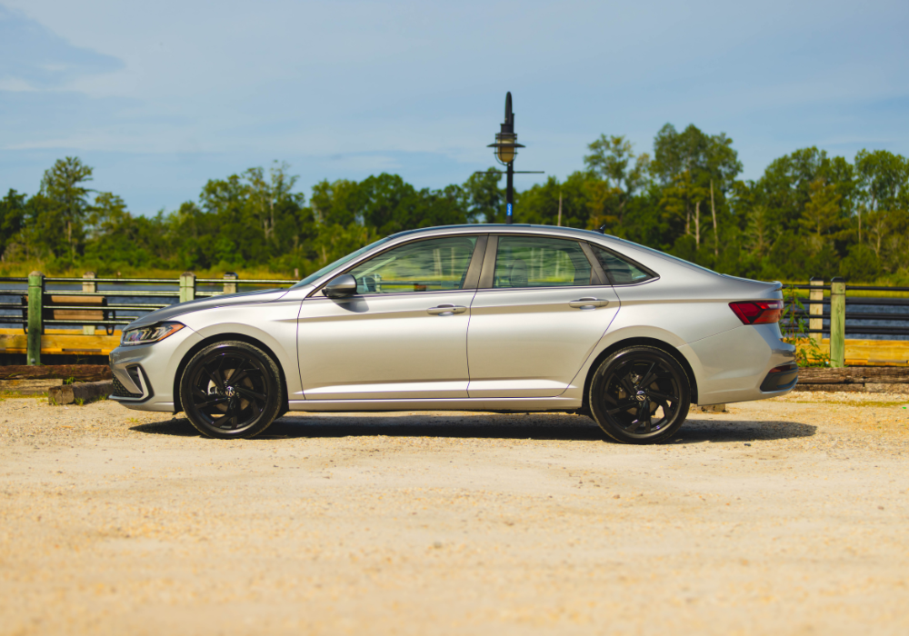 Driver's side view of a new Volkswagen Jetta parked in front of a large body of water